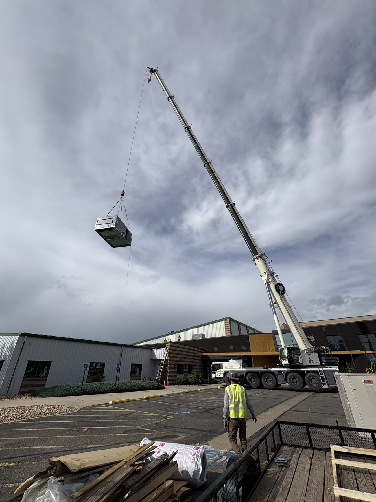 Crane setting a new rooftop HVAC unit on a commercial building