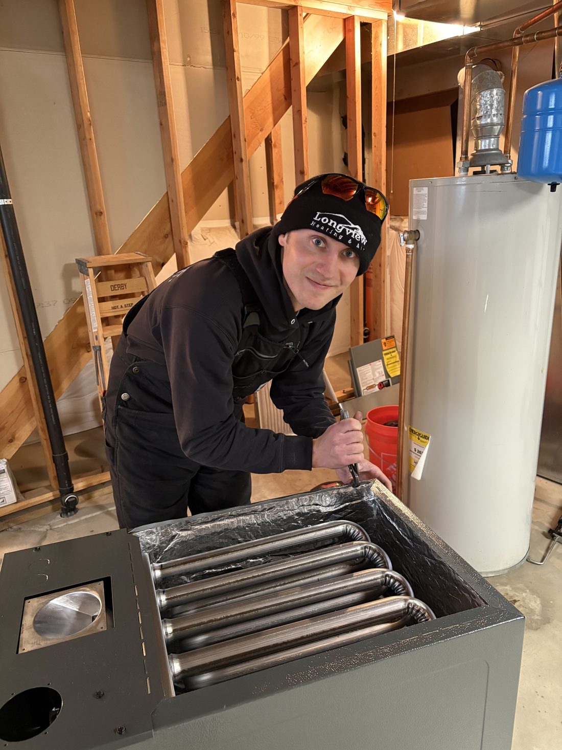 Longview technician with a new furnace during installation, heat exchanger visible
